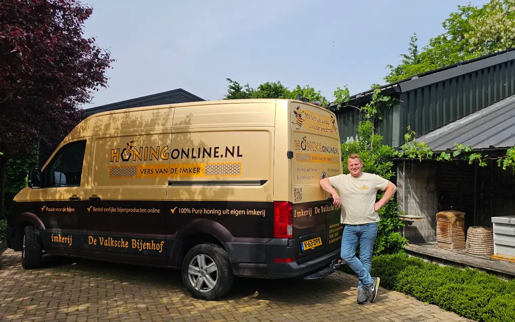Honing van de imker van HONINGonline.nl. Je ziet de imker Berthil van De Valksche Bijenhof staan bij zijn bus waarmee hij zuivere imkerhoning oogst.